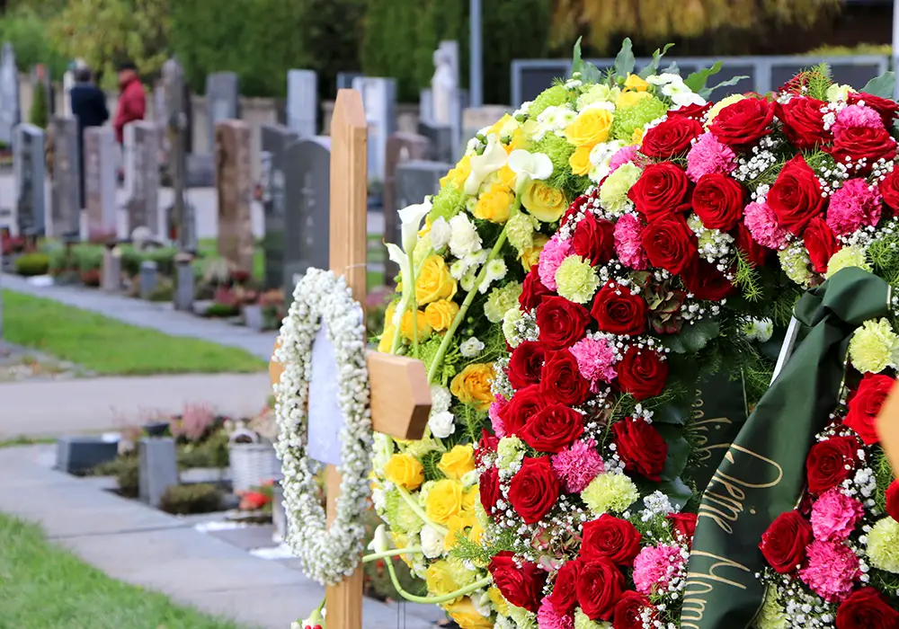 Blumenkränze an einem neuen Grab nach der Beisetzung